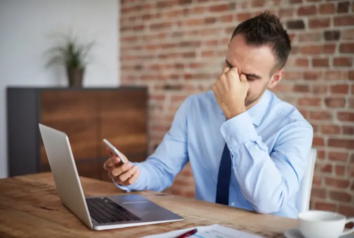 Person stressed while using laptop and smartphone
